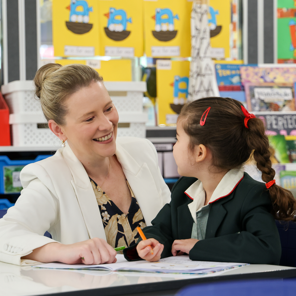 Teacher and Junior School student talking at a desk